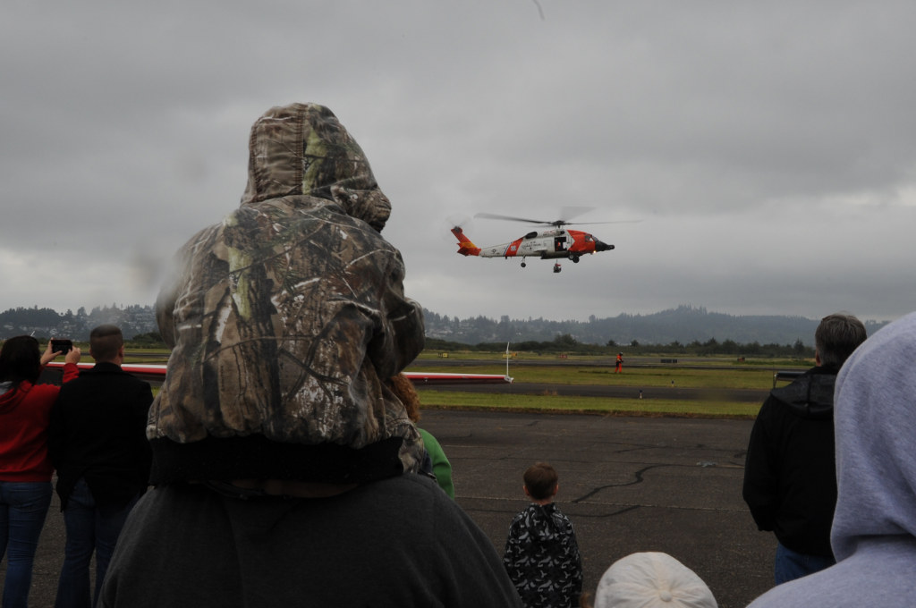 Families gather to watch the crew of an MH-60 Jayhawk helicopter perform a search-and-rescue demonstration during the Coast Guard Air Station Astoria Open House and Air Show Saturday, Sept. 17, 2011. Visitors to the air show were treated to displays by the Coast Guard, Coast Guard Auxiliary and National Guard as well as aerobatic flying by local pilots. Coast Guard photo by Petty Officer Shawn Eggert.