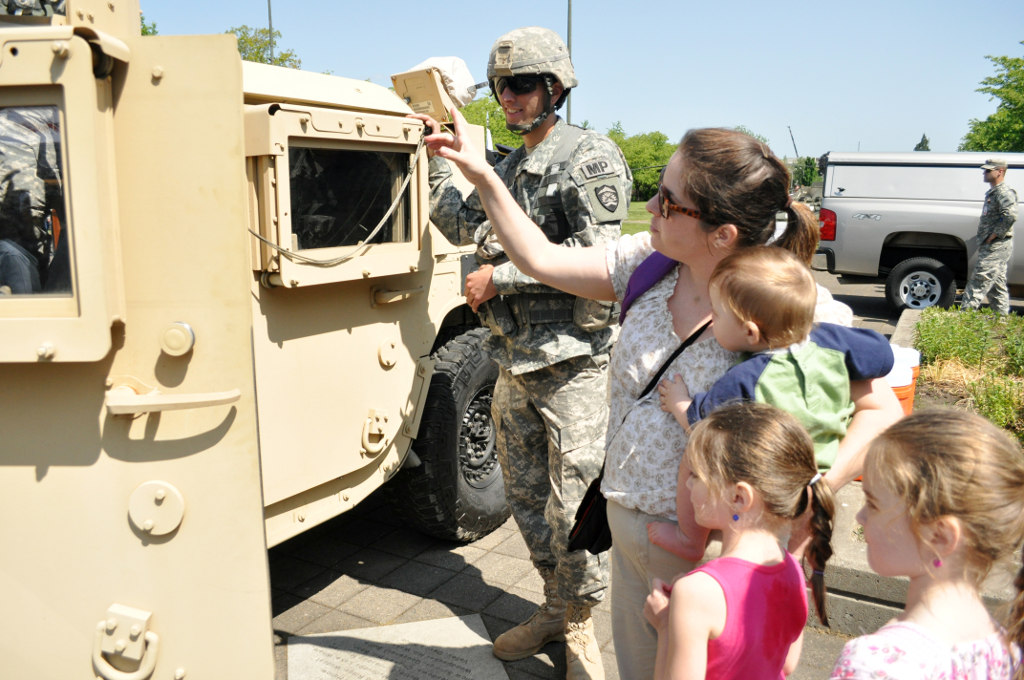 Spc. Jason Bell of the 1186 Military Police Company, Oregon Army National Guard, shows local children a Highly Mobile Multi-Wheeled Vehicle Spc. Jason Bell of the 1186 Military Police Company, Oregon Army National Guard, shows local children a Highly Mobile Multi-Wheeled Vehicle