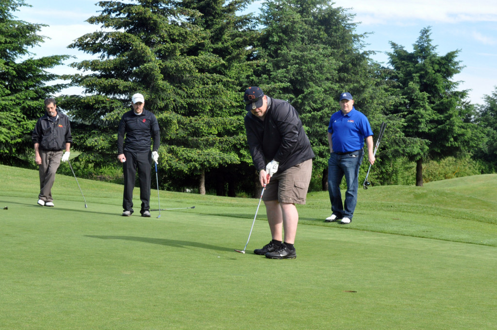 Tim McAlbin, with Columbia Helicopters, sinks a putt as his teammates, Bob DeFrancisco (left), Chad McCracken (center), and Oregon Army National Guard Lt. Col. Mike Gillette (right), watch during the 7th Annual Golfing for the Guard Tournament at Heron Lakes Golf Course, May 25. Tim McAlbin, with Columbia Helicopters, sinks a putt as his teammates, Bob DeFrancisco (left), Chad McCracken (center), and Oregon Army National Guard Lt. Col. Mike Gillette (right), watch during the 7th Annual Golfing for the Guard Tournament at Heron Lakes Golf Course, May 25.
