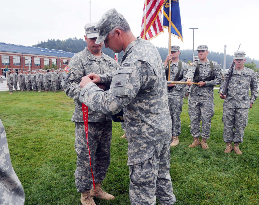 Lt. Col. Sean Nikkila (center), commander of the 41 Special Troops Battalion, affixes a Meritorious Unit Citation streamer to the battalion's guidon
